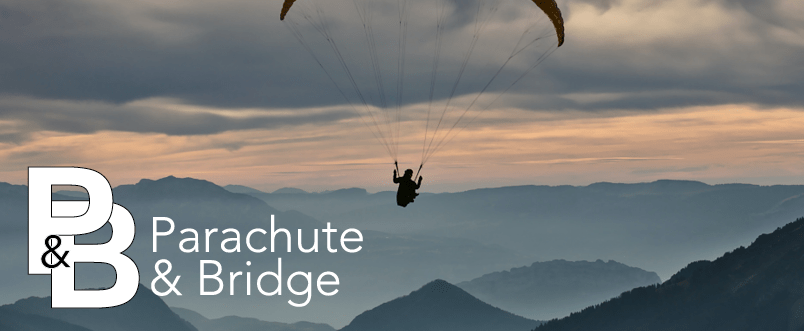 Image of a paraglider flying over a mountain range.